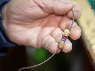 L�ultimo passaggio � l�infilaggio: un laccetto di cotone si fa passare dentro i noccioli e le perline per andare infine a fare un nodo